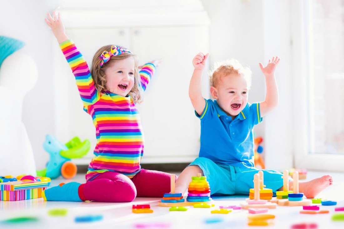 Two toddlers cheering while playing with colorful blocks