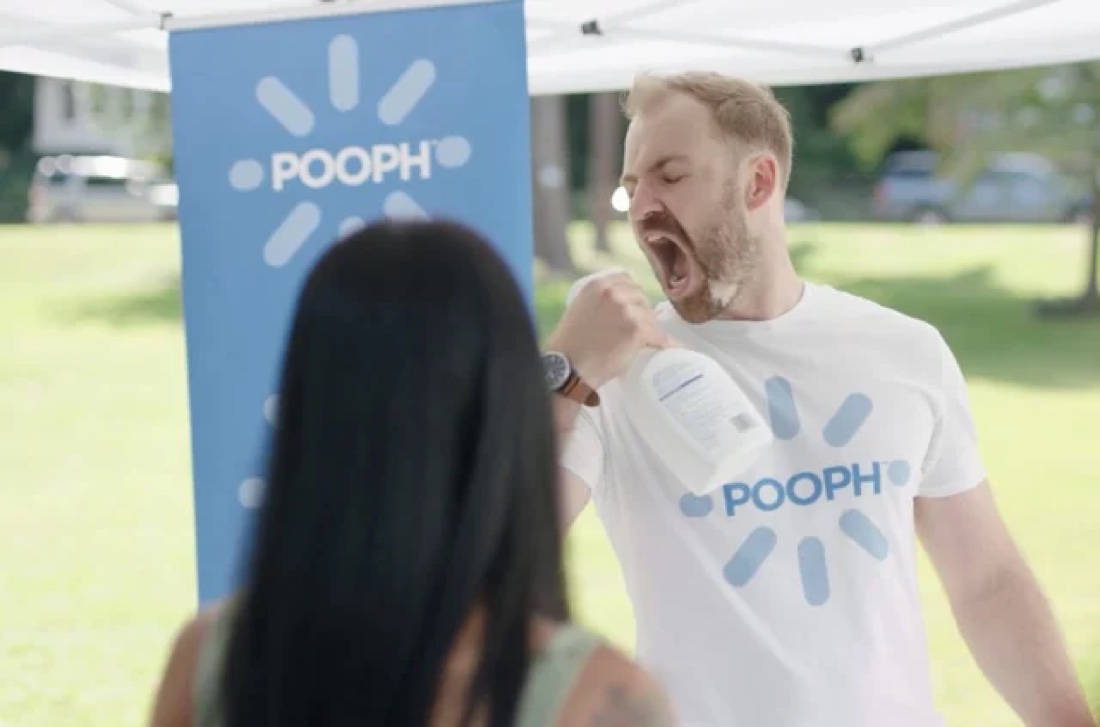 A still from the Pooph commercial: a man sprays Pooph toward his mouth to show it is non-toxic